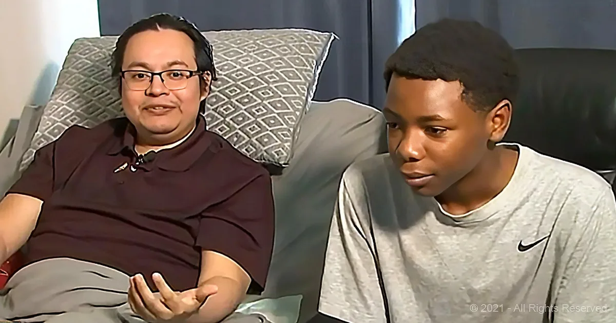 Two individuals are seated on a couch, one wearing glasses and a maroon shirt, the other in a gray Nike shirt, engaged in...