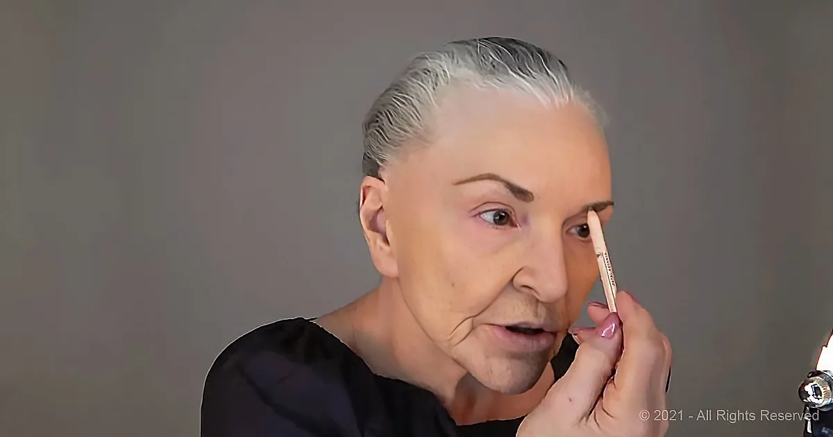 A person with white hair is applying makeup, focusing on their eye area.