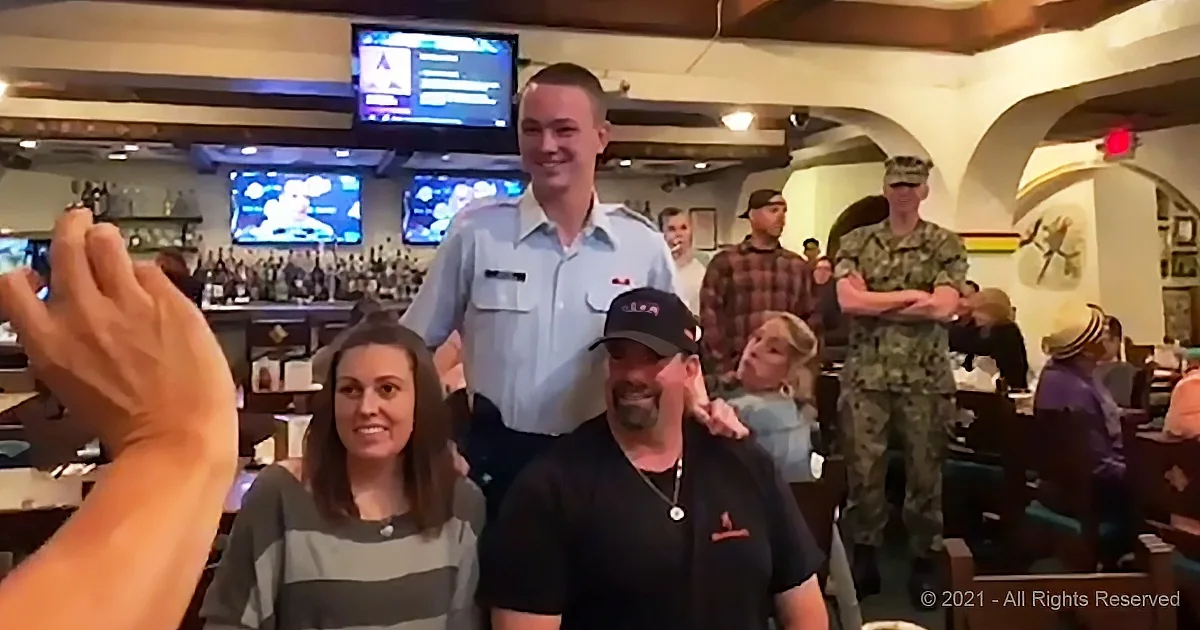 A group of people, including a man in a military uniform, are posing for a photo in a bar setting.
