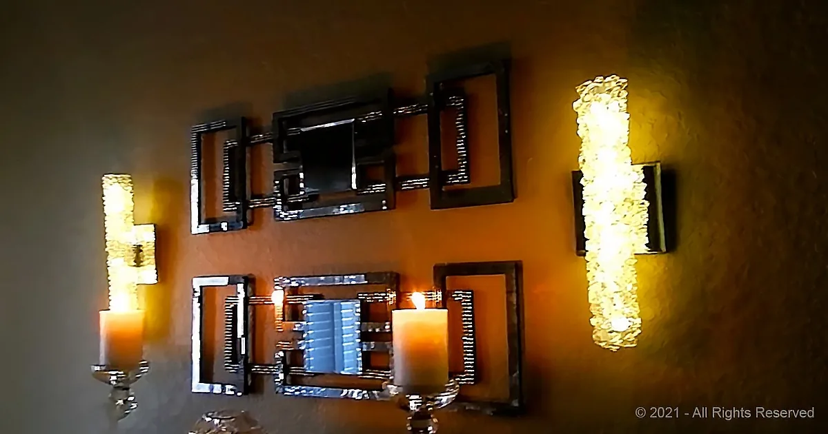 I see a wall with two sets of decorative mirrors flanked by illuminated candle sconces.