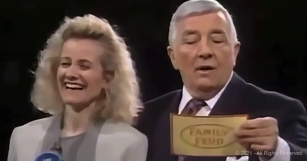 A man in a suit holds a "Family Feud" card while a woman smiles beside him.