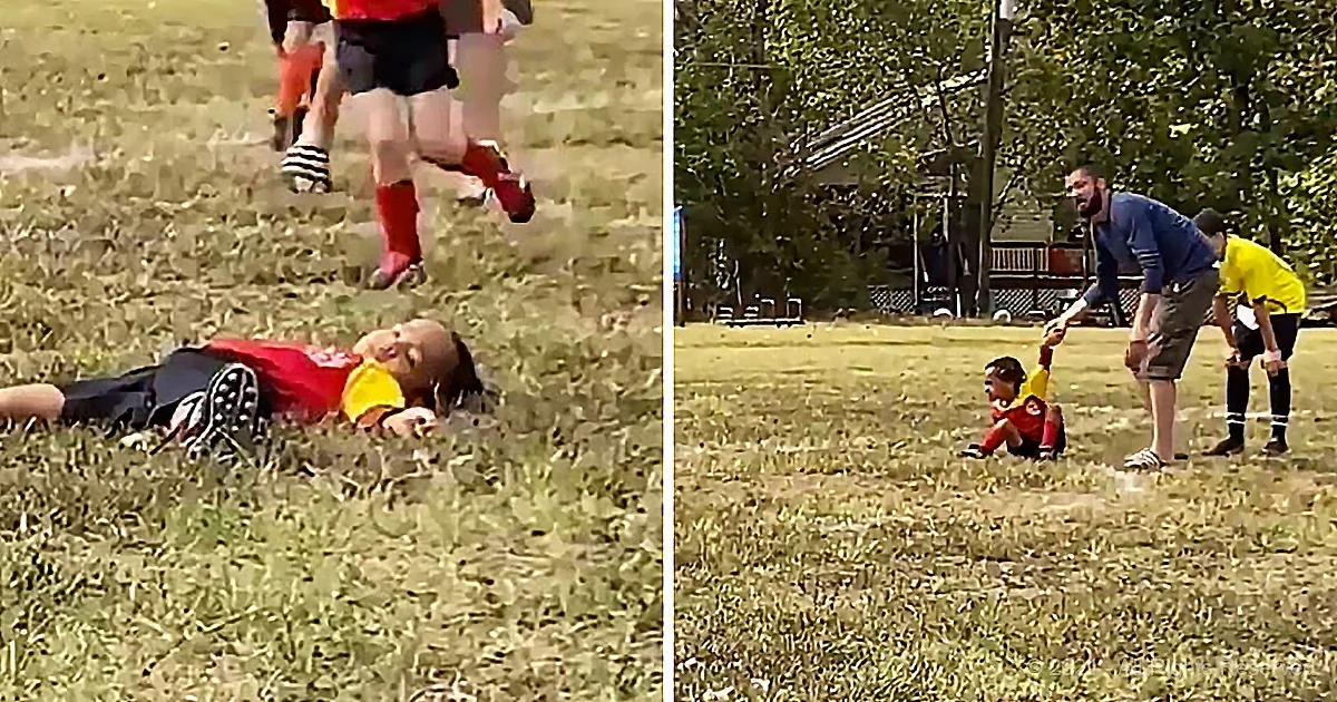 A child in a red shirt lies on the grass, while another child in a yellow shirt runs nearby, and an adult bends down to...