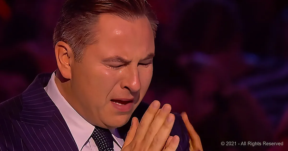 A man in a suit and tie is seen with his hands clasped, appearing emotional or in deep thought.