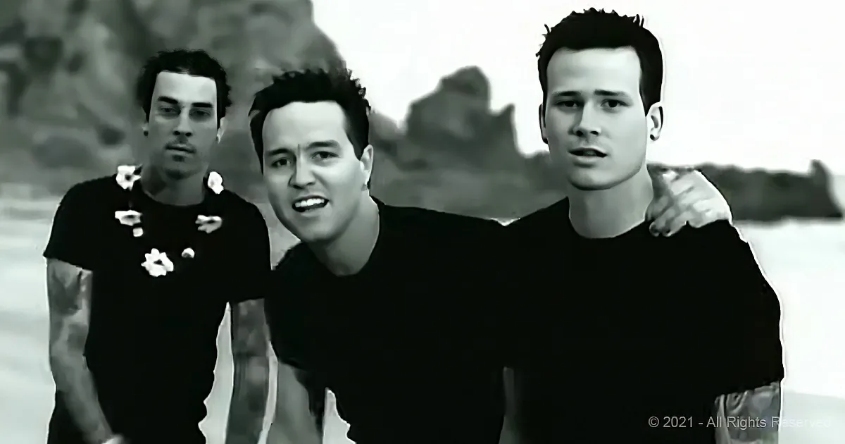 Three men in black shirts, one with flowers, standing together, smiling, in a black-and-white image.