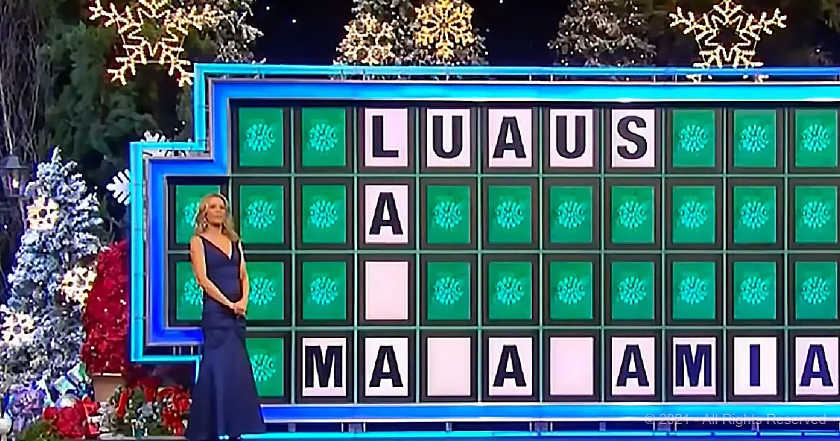 A woman in a dark dress stands in front of a Scrabble board with "LUAS" and "MALAMIA" displayed.