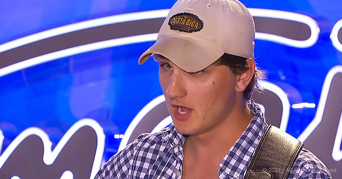A person wearing a Costa Rica cap and checkered shirt is speaking in front of a blue background.