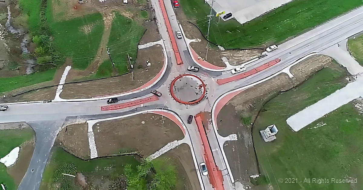 Aerial view of a roundabout with vehicles and surrounding greenery.
