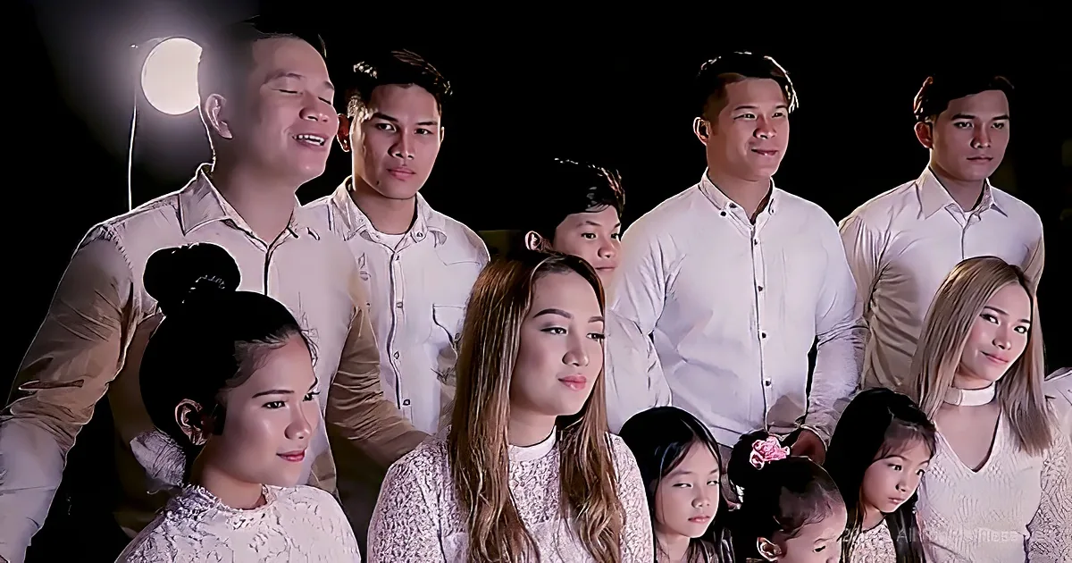A group of people in white attire, including adults and children, posing together in a photo.
