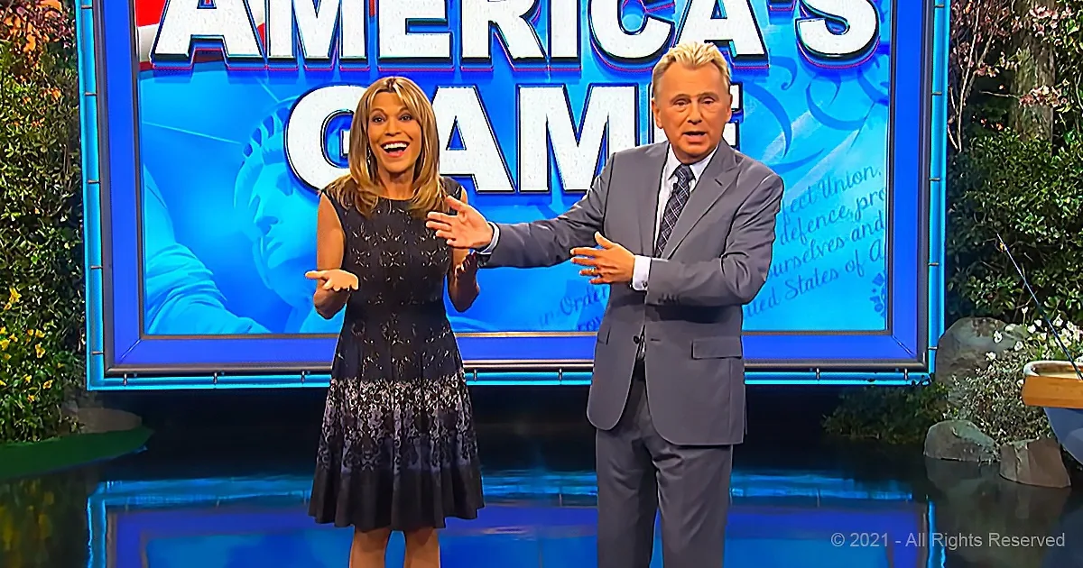 A man in a suit and a woman in a dress stand in front of a "America's Game" sign, gesturing animatedly.