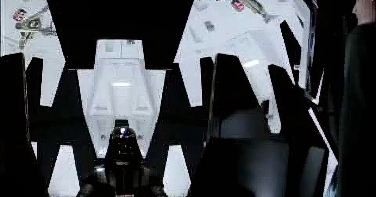 Darth Vader stands in a dimly lit room, wearing his iconic black helmet and armor.