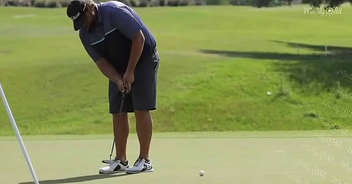 A golfer in a blue outfit bends over to line up a putt on a green.
