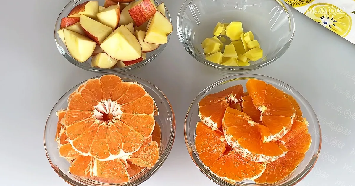 Four glass bowls with sliced apples, pineapple, and oranges on a white surface.