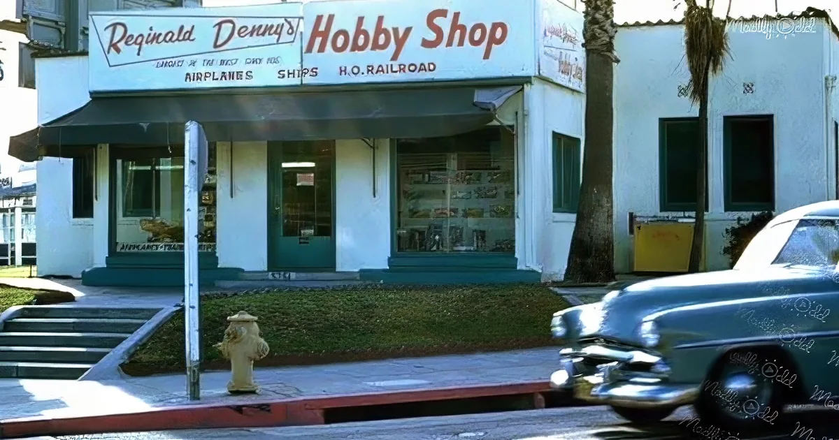 A vintage hobby shop with "Reginald Denny's Hobby Shop" sign, offering airplanes, ships, and H.O. Railroad models.