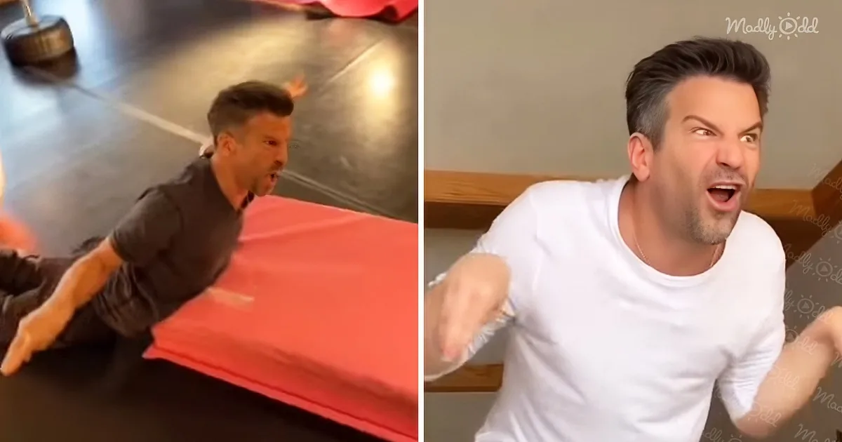 A man in a white shirt is making an exaggerated expression, while another man in a black shirt is sliding on a red mat.