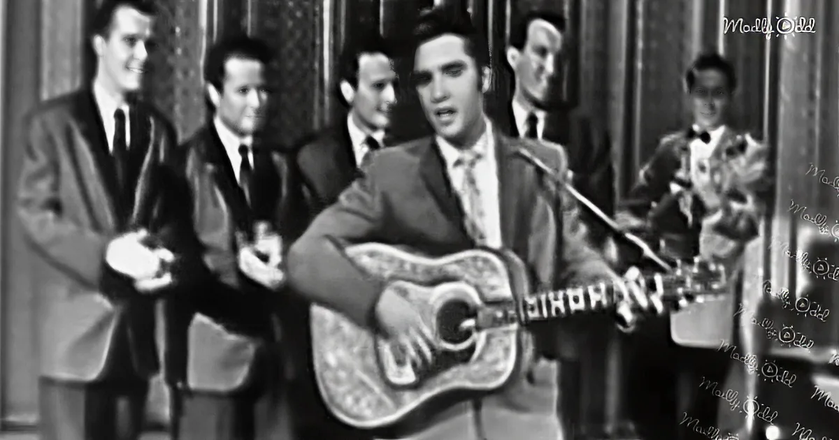 Elvis Presley plays guitar on stage with a band, singing passionately.