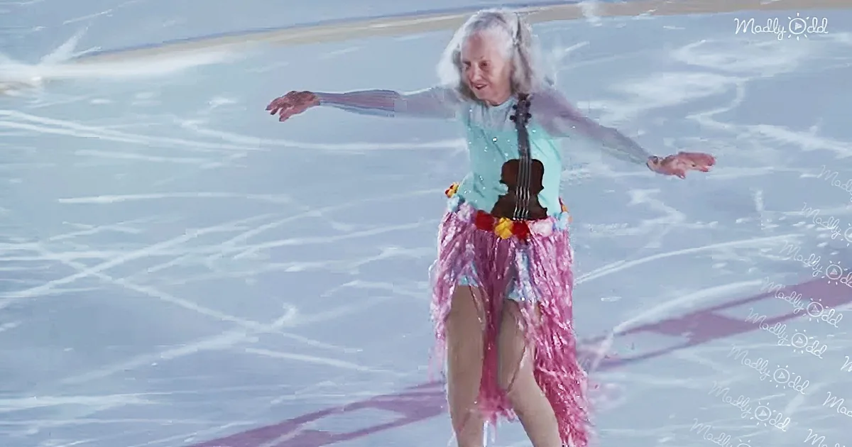 An elderly woman in a colorful outfit is ice skating with a violin, arms outstretched.