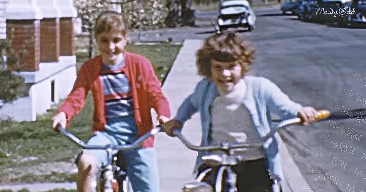 Two children riding bicycles on a suburban street, smiling and enjoying their ride.