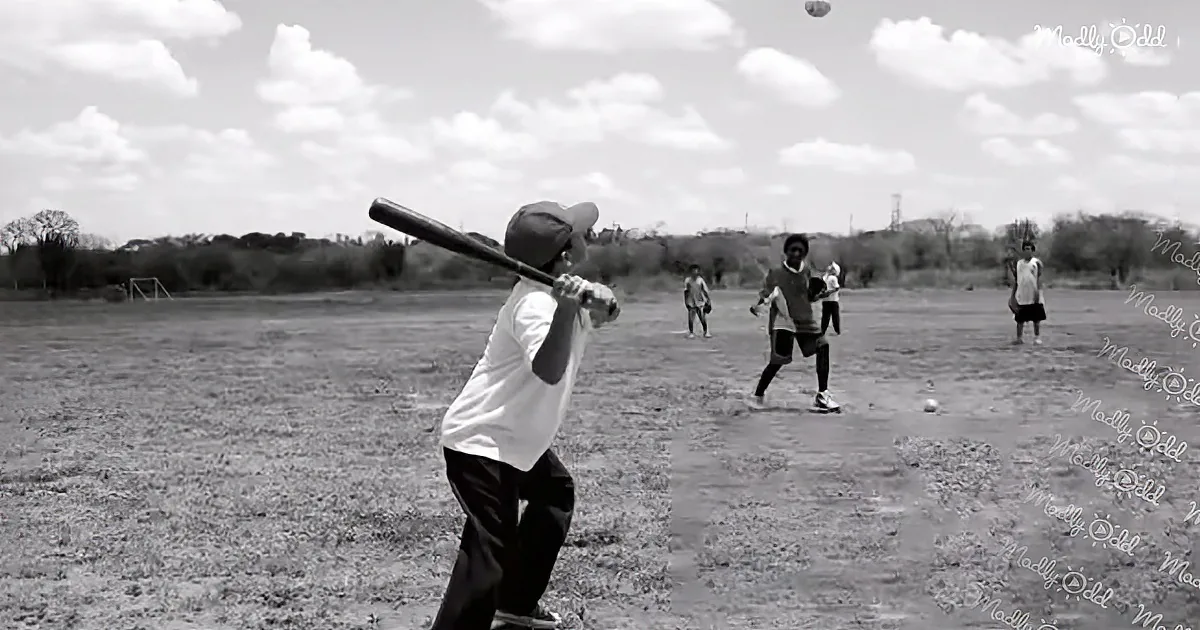 A boy swings a bat in a black-and-white image of a baseball game on a field.
