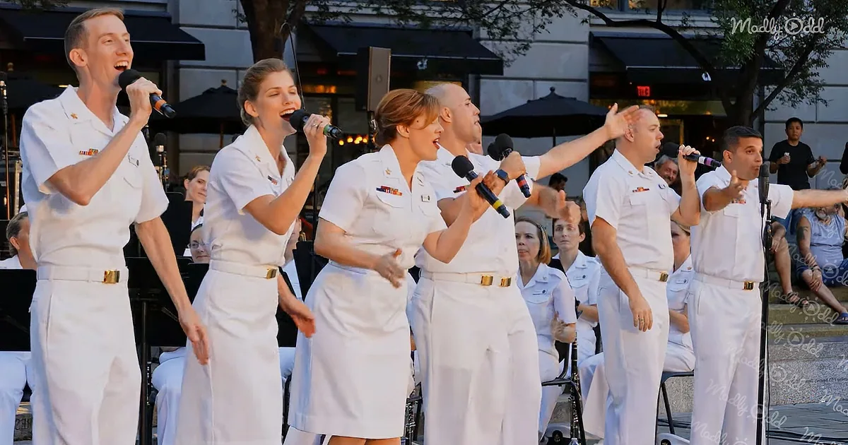 A group of uniformed singers in white perform energetically on stage.