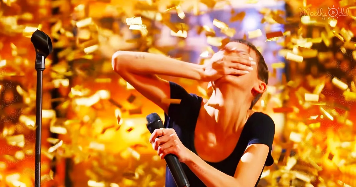 A person holding a microphone with arms raised amidst falling confetti, creating a celebratory atmosphere.