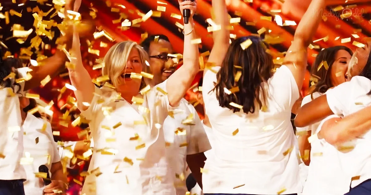 A group of people in white outfits celebrates with raised arms amidst falling gold confetti.