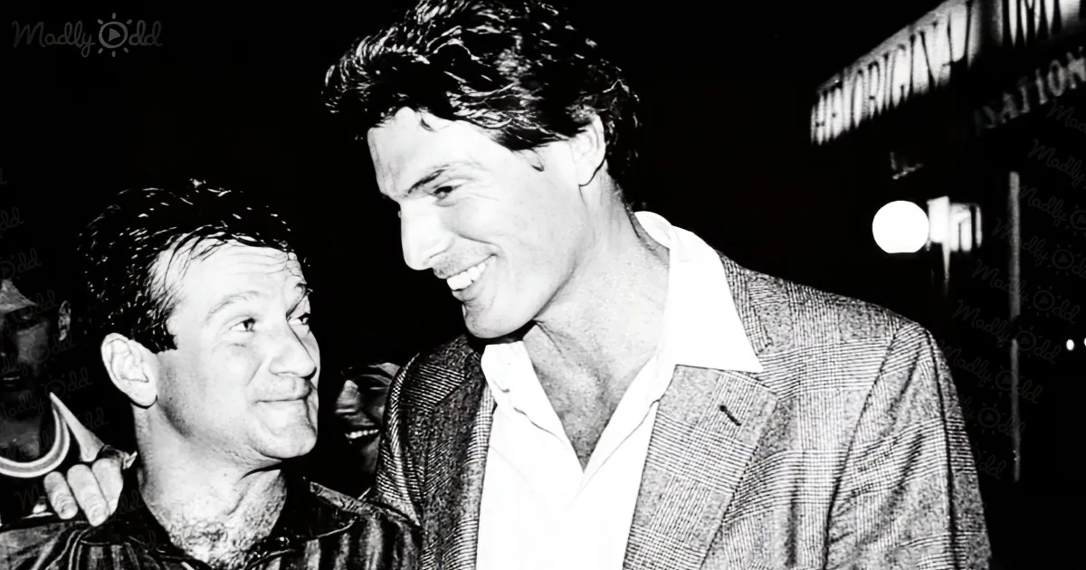 Two men, one in a suit, share a warm smile in a black-and-white photo.