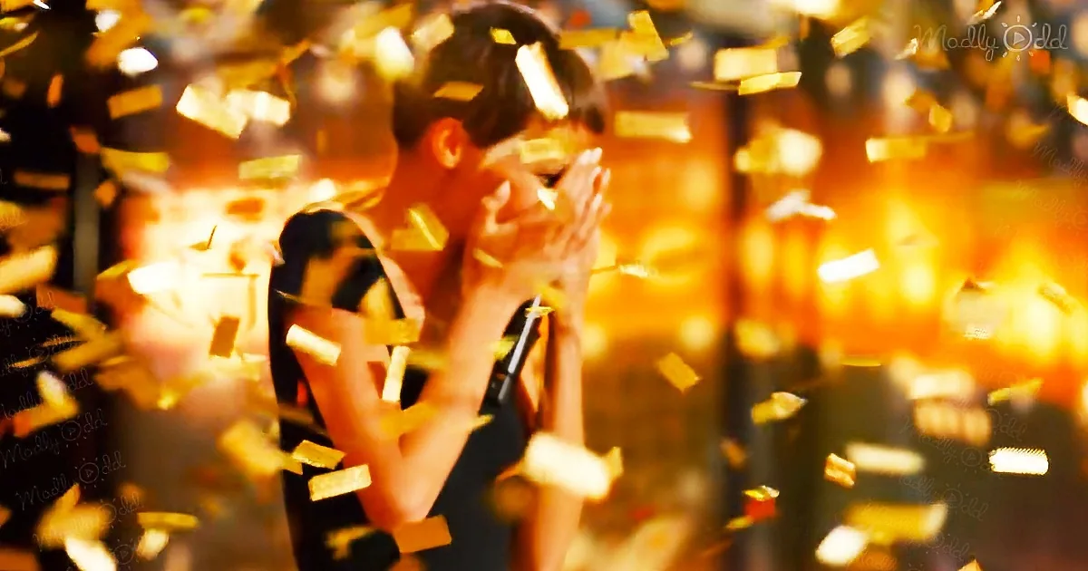 A person with hands near face, surrounded by golden confetti, creating a celebratory atmosphere.