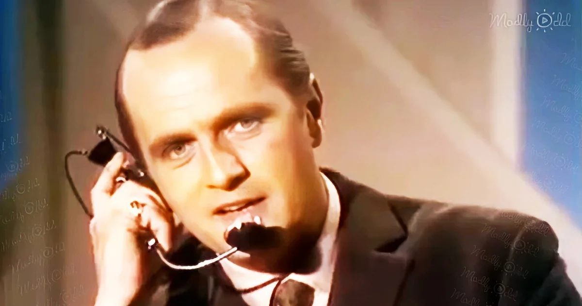 A man in a suit and tie is holding a phone to his ear, appearing to be in a serious conversation.