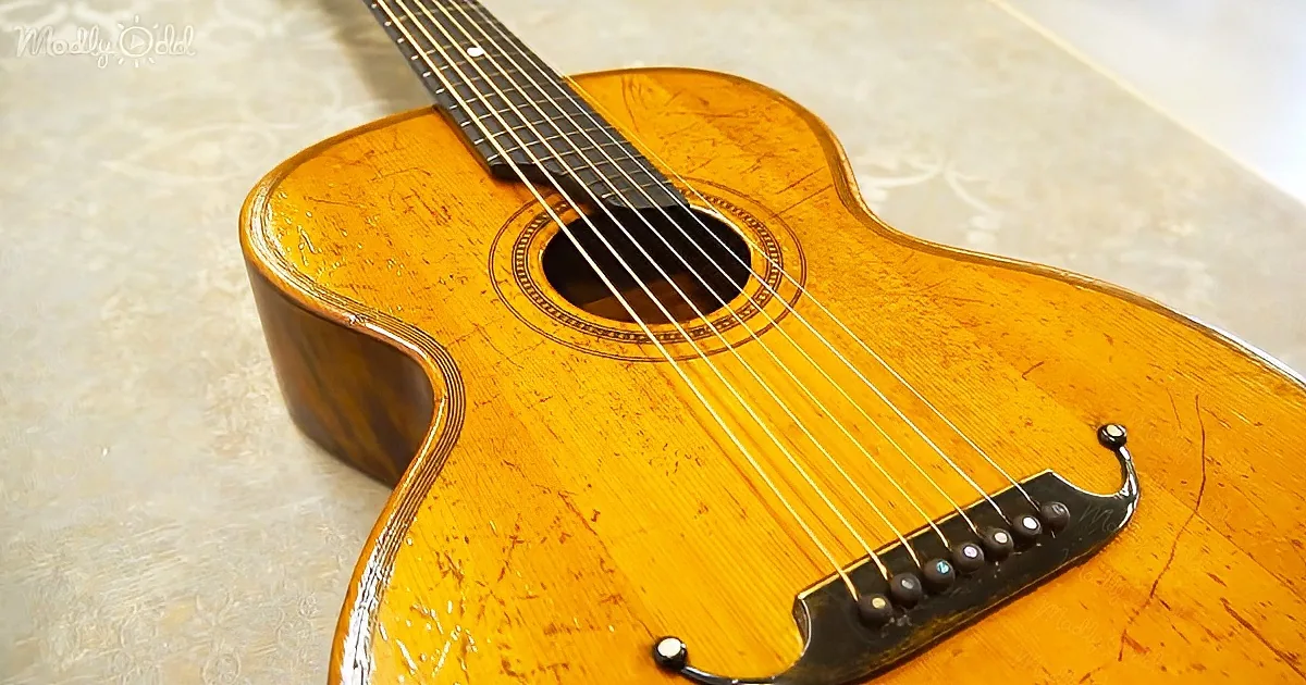 A close-up of a vintage-style acoustic guitar with a glossy finish and intricate wood grain.