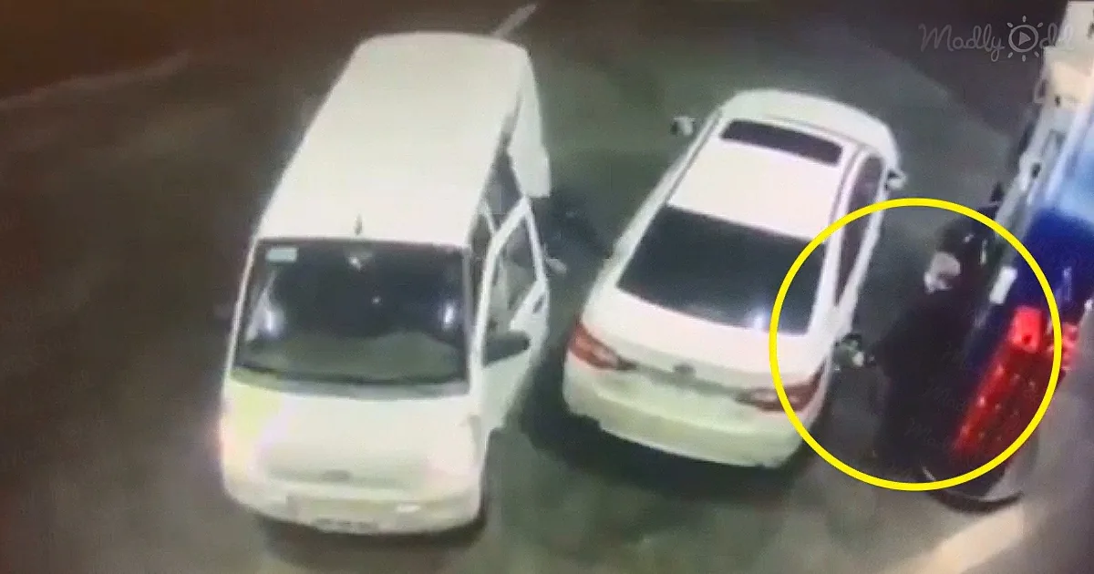 A white van is parked next to a white sedan in a dimly lit parking area.