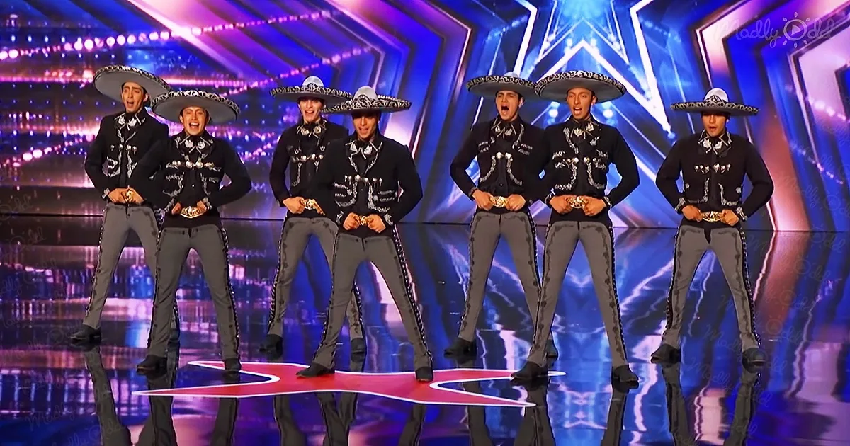 A group of seven men in traditional Mexican attire perform on a brightly lit stage.