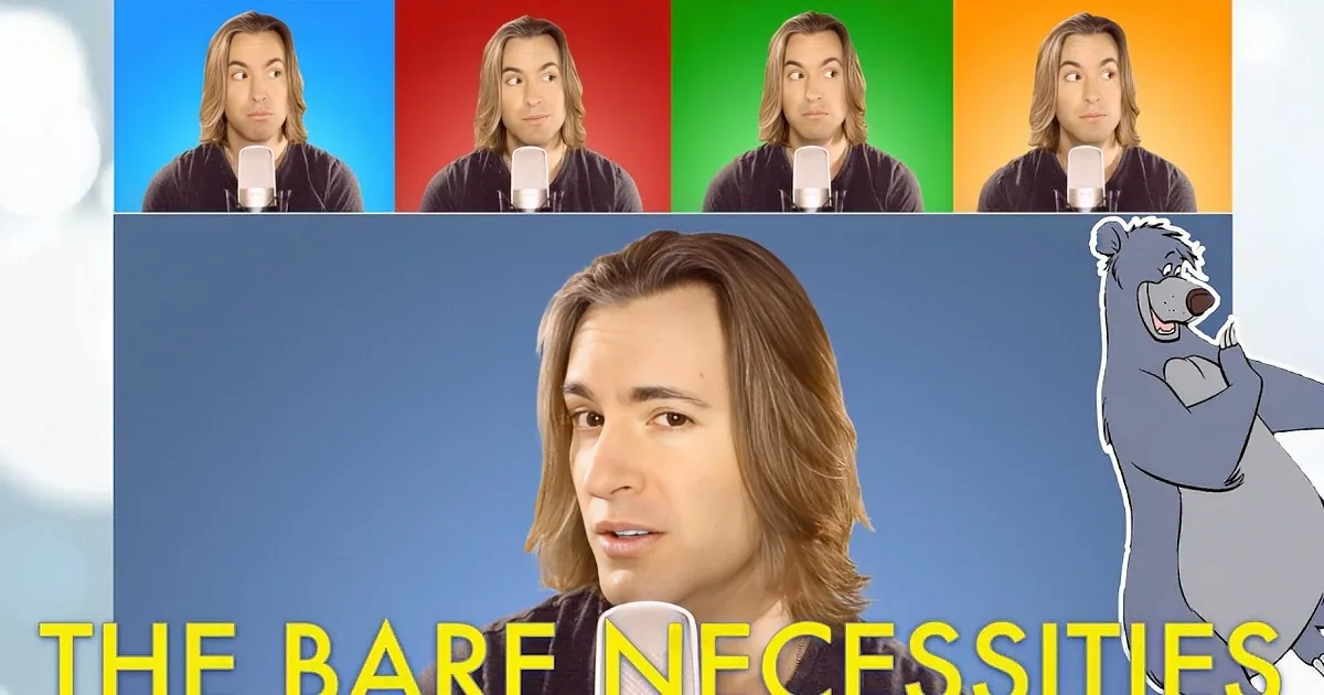 A person with long hair and a dark shirt speaks into a white microphone against a blue background.