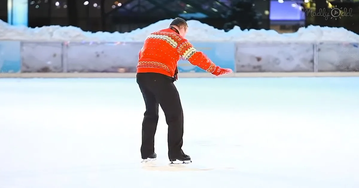 A person in a red sweater and black pants skates on an ice rink, leaning forward with one arm extended.