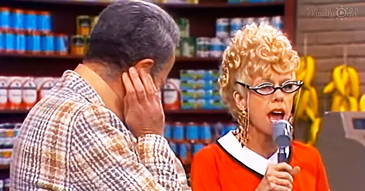 Woman in orange sweater holds microphone, man in plaid shirt covers ear, grocery store shelves in background.