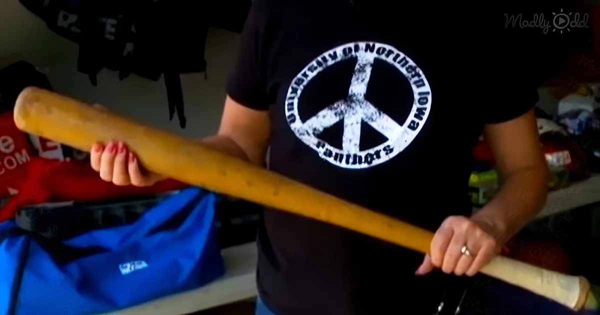 A person wearing a University of Northern Iowa Panthers shirt holds a wooden bat.