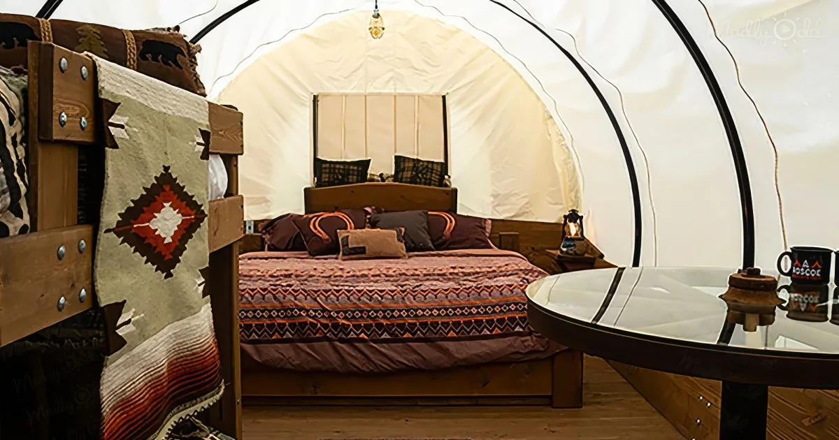 A cozy, rustic tent interior with a bed, wooden furniture, and Native American-inspired decor.