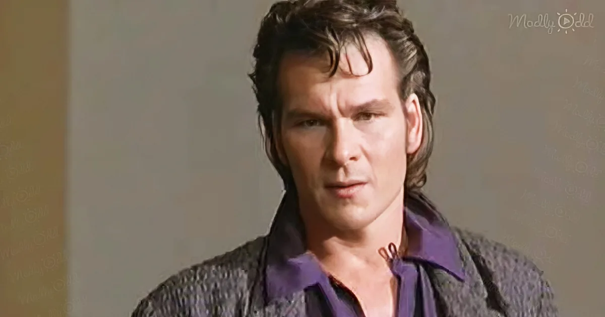 A man with dark hair, wearing a purple shirt and textured jacket, looks intense.