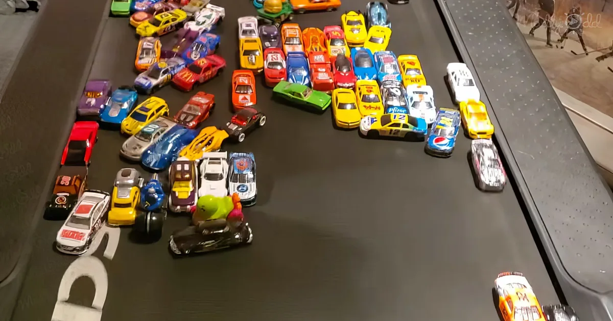A collection of colorful toy cars, including NASCAR-style race cars, are displayed on a black surface.