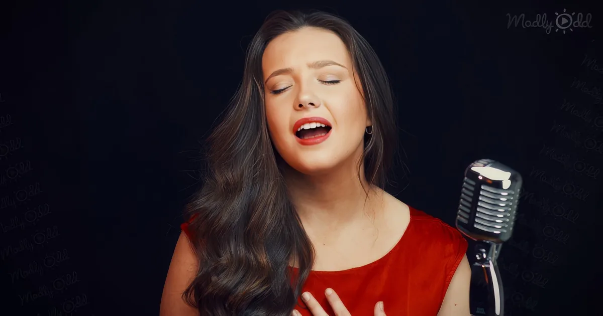 A woman in a red dress sings passionately into a vintage microphone against a dark background.