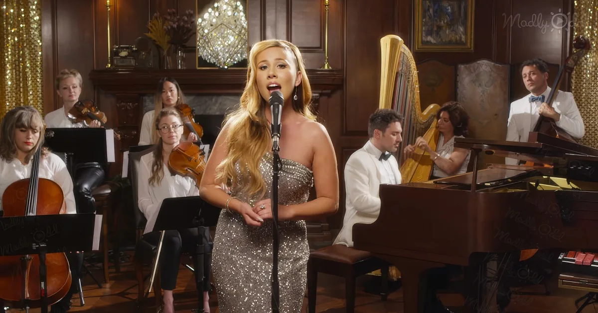 A woman in a sequined dress sings into a microphone, surrounded by musicians in a formal setting.