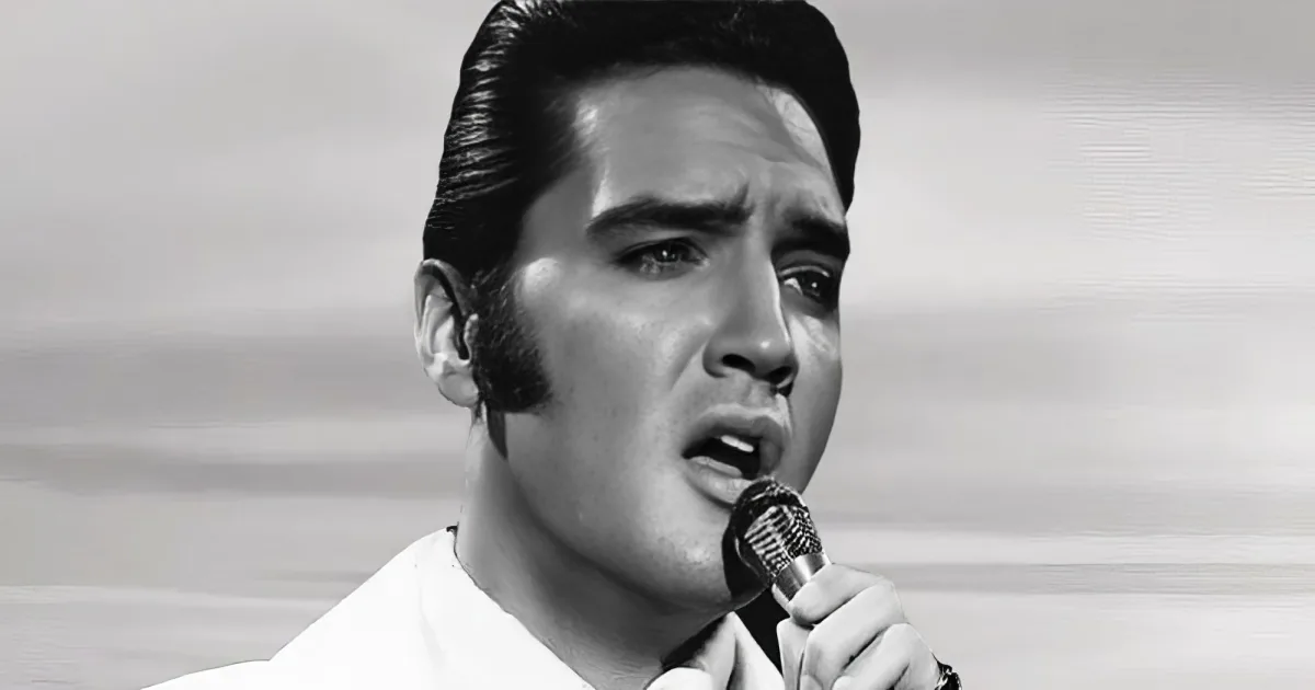 A black-and-white image of Elvis Presley singing into a microphone, wearing a white shirt.