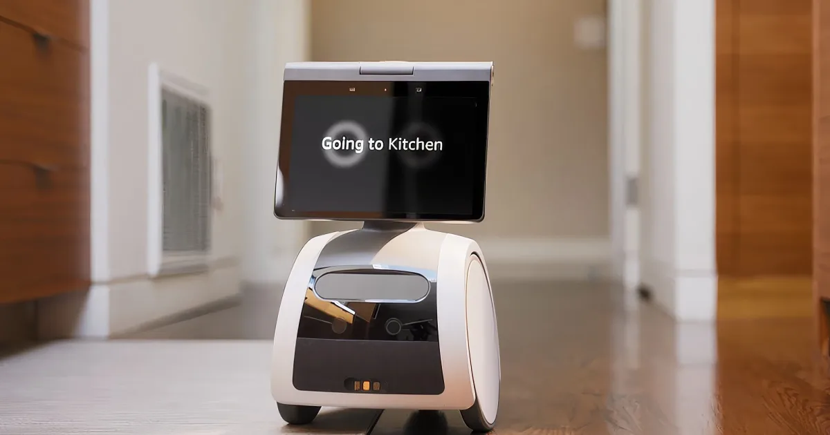 A robot with a screen saying "Going to Kitchen" is on a wooden floor, heading towards a kitchen.