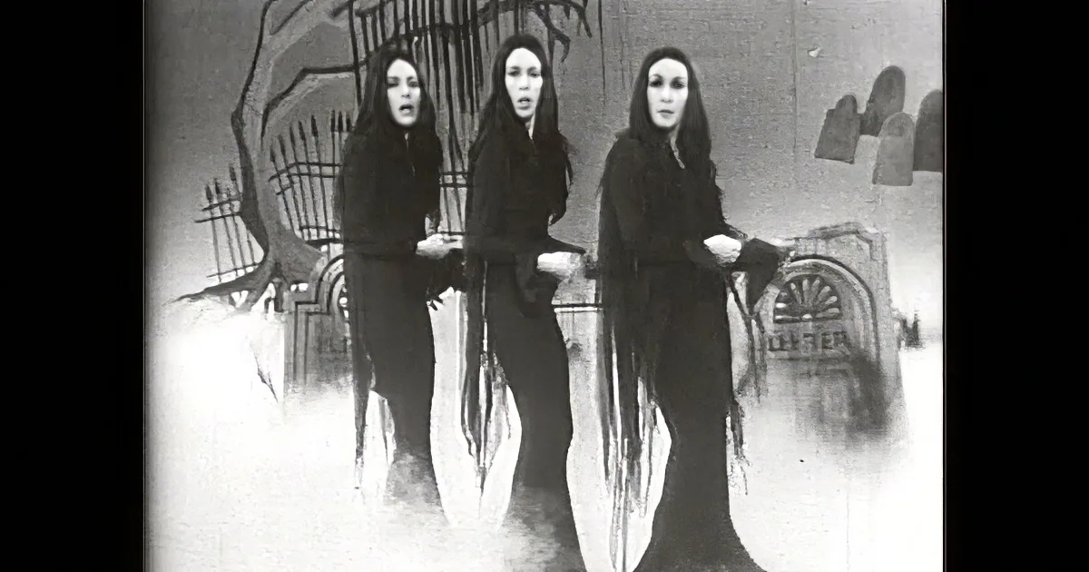 Two women in dark attire are engaged in a conversation, with one gesturing while the other listens attentively.