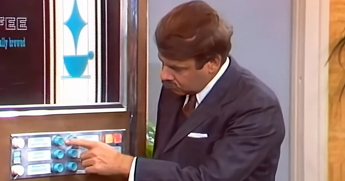 A man in a suit is holding a tray with blue cups, looking down at it.