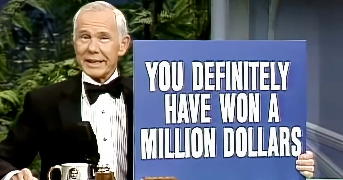 A man in a tuxedo stands behind a podium with a sign saying "You definitely have won many dollars."