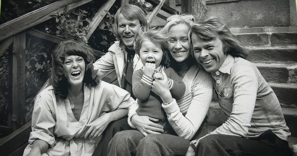 A family of five, including a child, sits together outdoors, smiling and laughing.