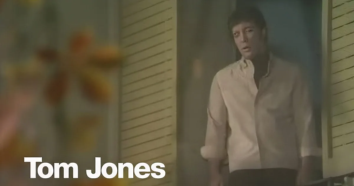A man in a white shirt looks up, possibly in surprise or concern, with a blurred background.