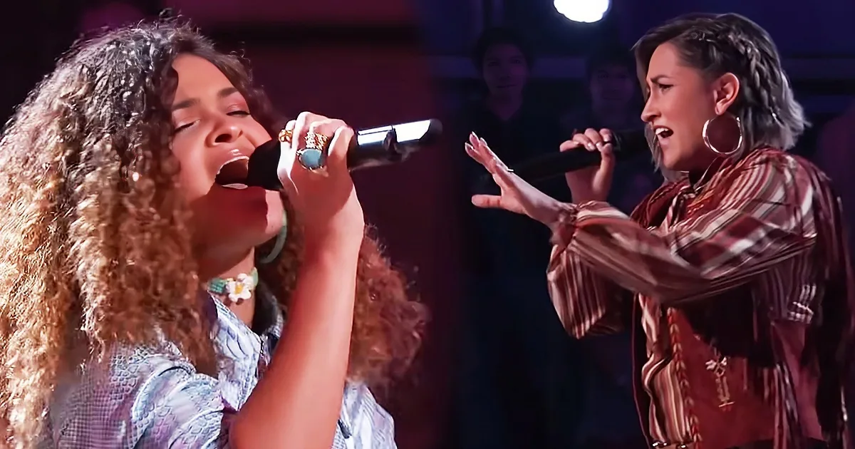 Two women sing passionately on stage, one with long curly hair, both holding microphones.