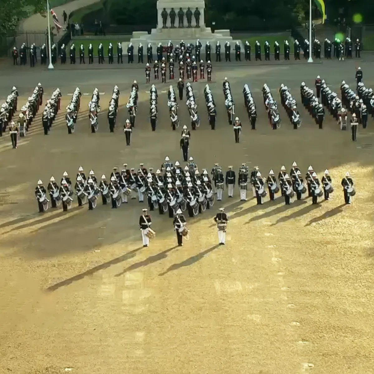A military band in formation with drums and trumpets, standing in a large open area.