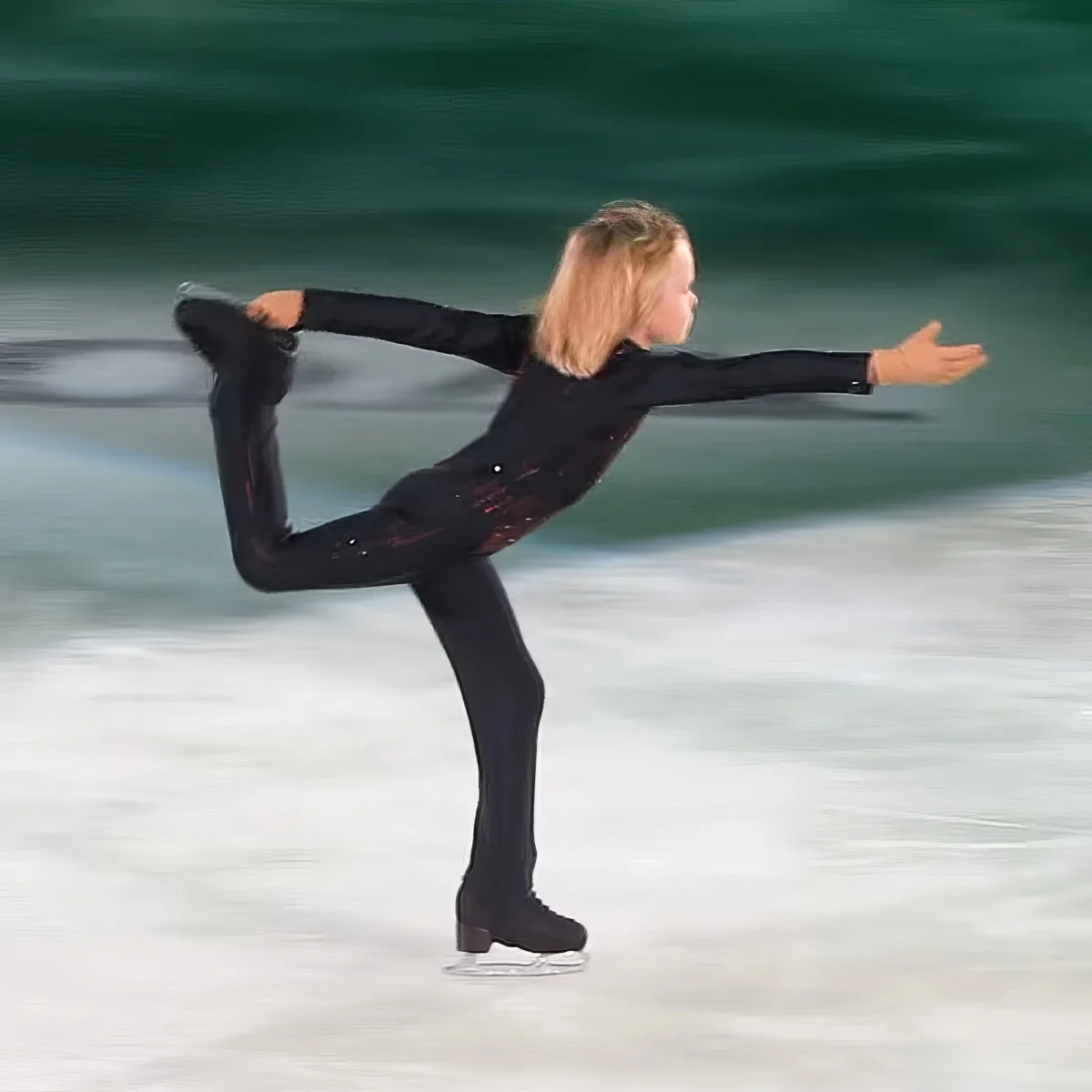 A figure skater in a black outfit performs a graceful pose on ice with one leg extended.